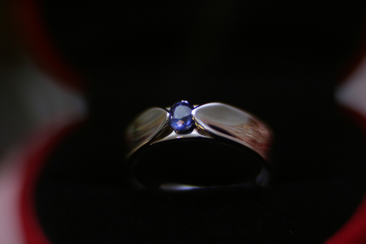 A close up of a wedding band with oval blur sapphire center stone.