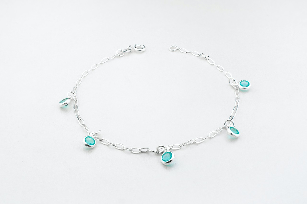 a white gold chain bracelet with station-set blue gemstones