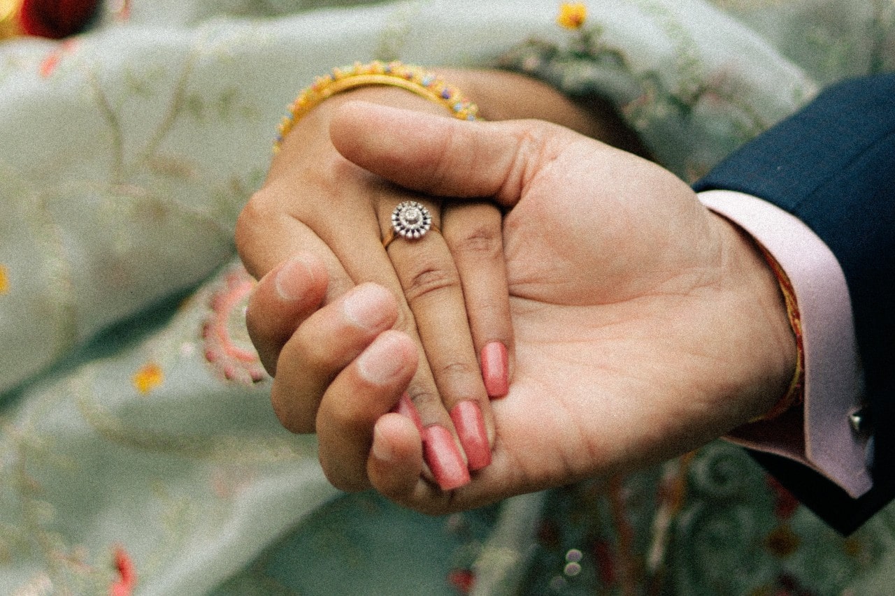 man’s hand holding a lady’s while wearing an engagement ring man’s hand holding a lady’s while wearing an engagement ring