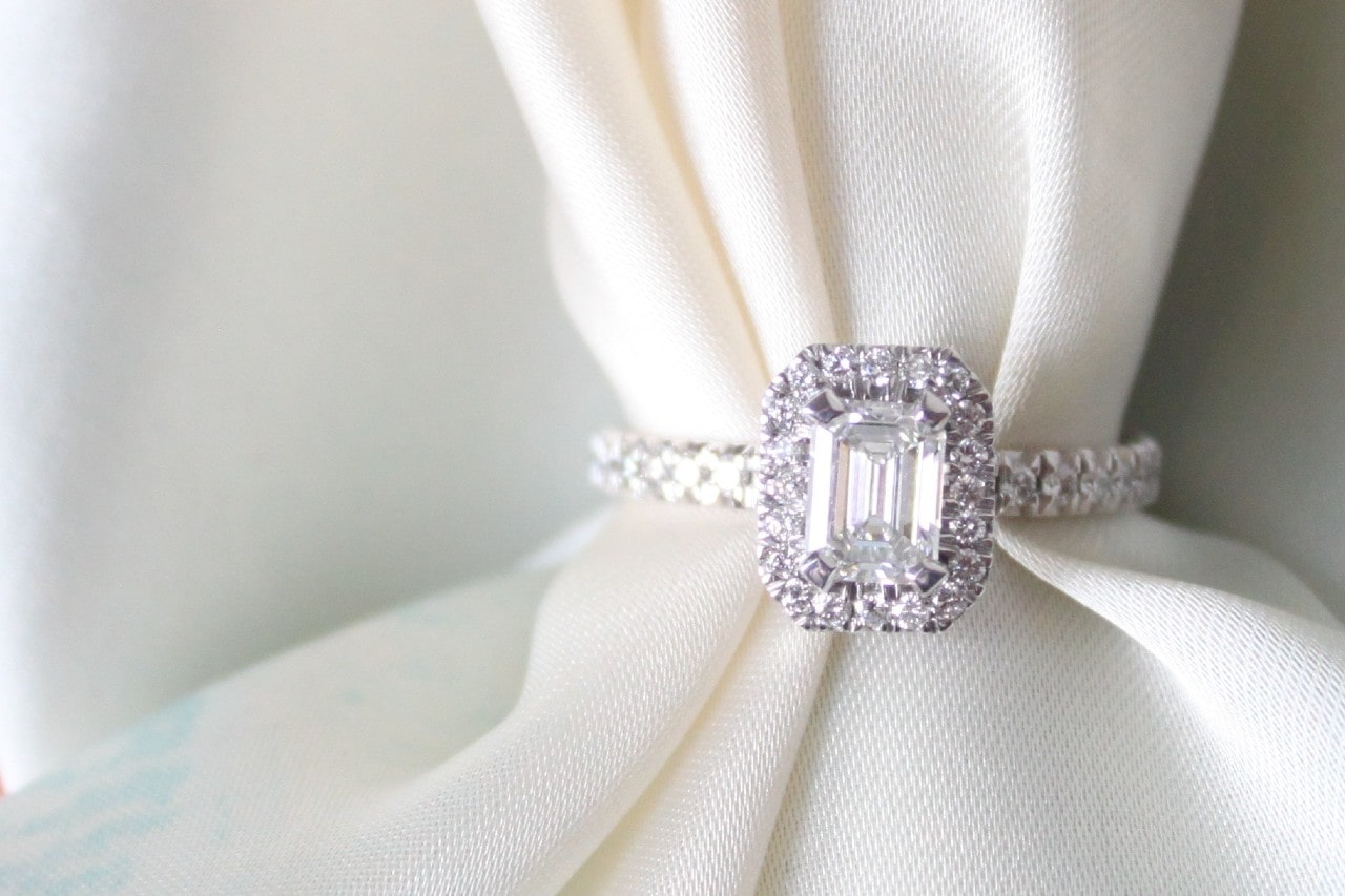 emerald cut halo engagement ring wrapped around a white cloth emerald cut halo engagement ring wrapped around a white cloth