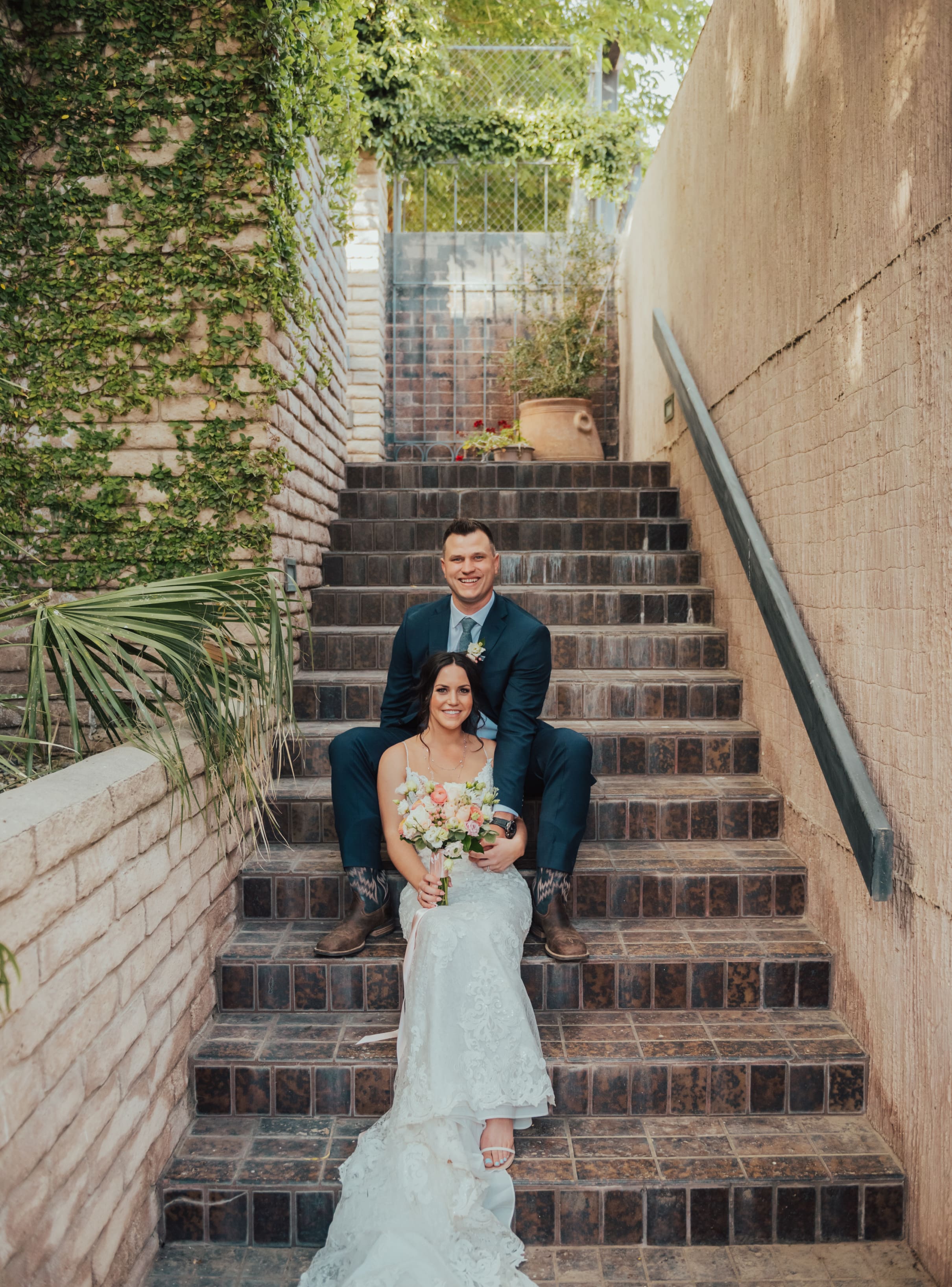 Karlie Tanner & Spouse Karlie Tanner sitting on a staircase. Her husband sits behind her a few steps above.