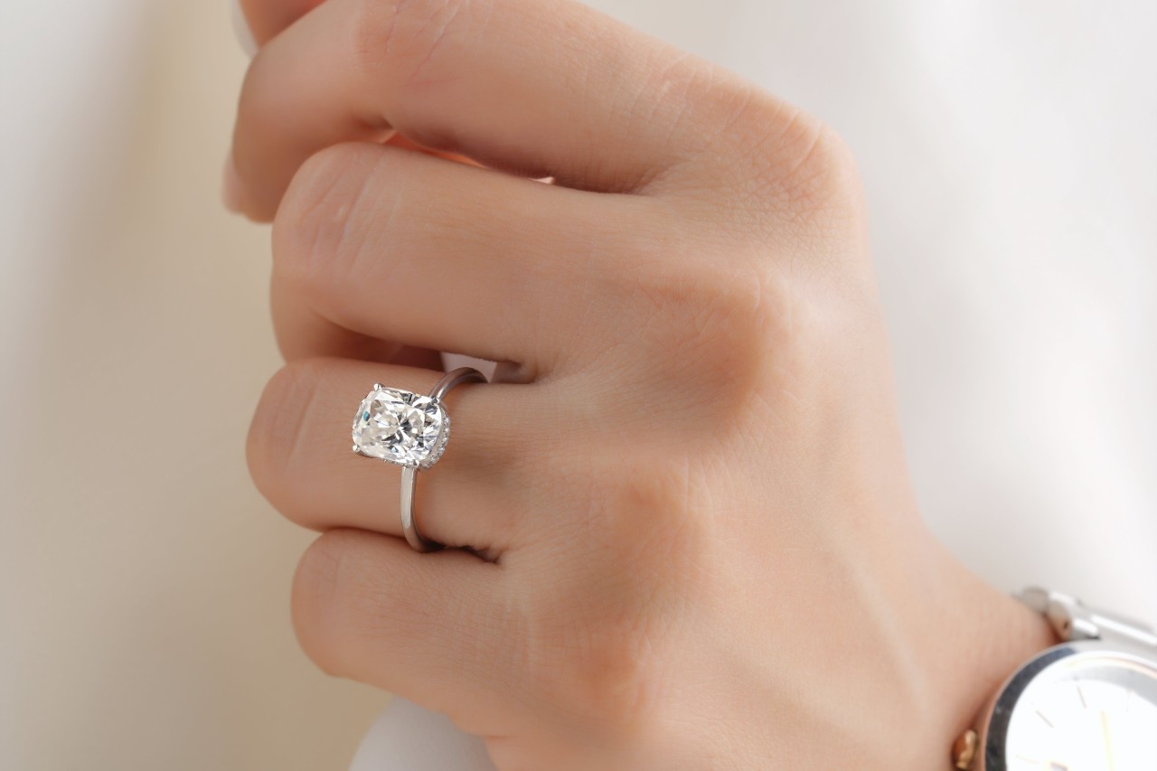A closeup of a woman’s hand, wearing a platinum solitaire ring.