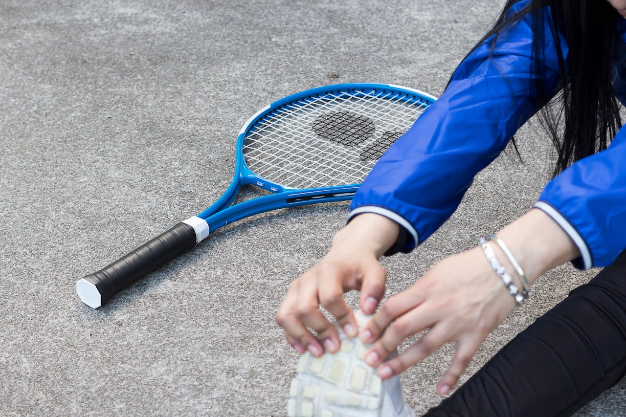A view of a tennis player stretching before a match, wearing a tennis bracelet on her left wrist.