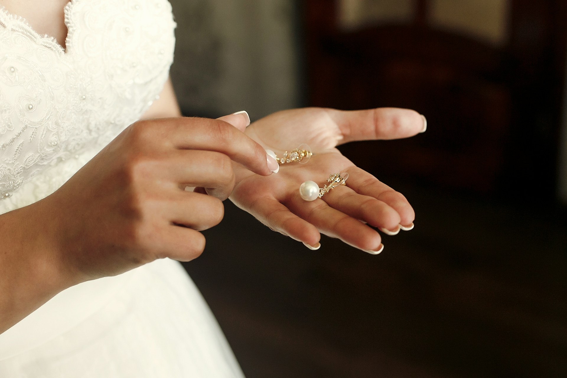 A close-up of a bride-to-be holding a pair of pearl earrings in her palm. A close-up of a bride-to-be holding a pair of pearl earrings in her palm.